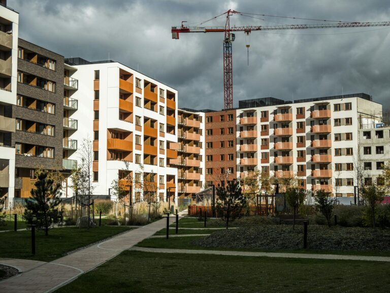 Newly built residential buildings under cloudy skies with a construction crane.